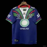 Camisa Heritage 25/26 do New Zealand Warriors, azul marinho com listras diagonais verdes e vermelhas e degradê circular. Camisa Heritage 25/26 do New Zealand Warriors, azul marinho com listras diagonais verdes e vermelhas e degradê circular.